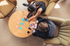 Businesspeople discussing over adhesive notes in office lobby